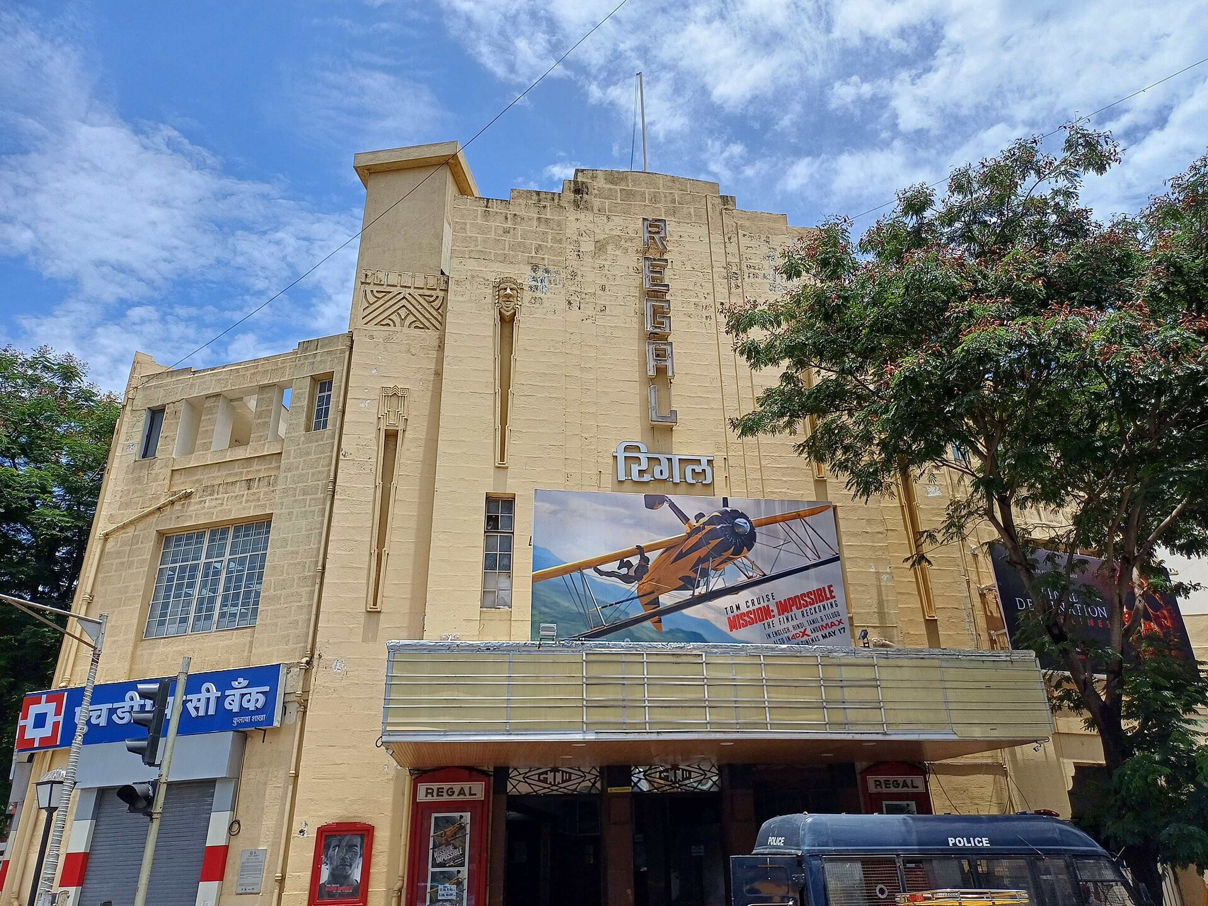 Facade of the Regal cinema building with a film poster on its upper wall and a police van at the entrance.