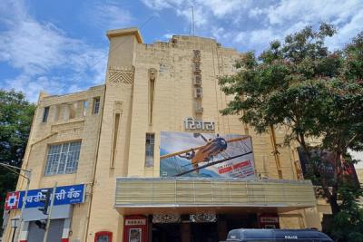 Facade of the Regal cinema building with a film poster on its upper wall and a police van at the entrance.