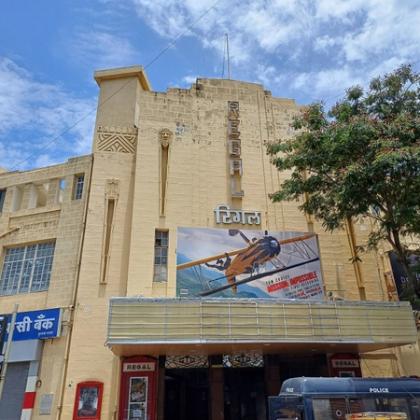Facade of the Regal cinema building with a film poster on its upper wall and a police van at the entrance.