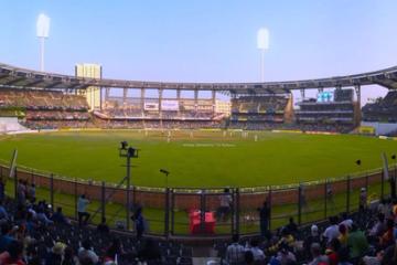 Panoramic view of Wankhede Stadium with crowded stands and players on the pitch in the evening light.