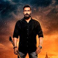 Bearded man in a black shirt holding a tool at his side, standing in rain under a dark, stormy orange sky