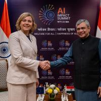 Ashwini Vaishnaw and Henna Virkkunen shake hands before an AI Impact Summit backdrop with Indian and EU flags.