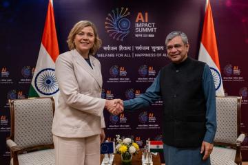 Ashwini Vaishnaw and Henna Virkkunen shake hands before an AI Impact Summit backdrop with Indian and EU flags.