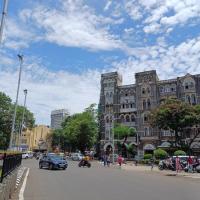 Mumbai street with traffic and pedestrians in front of a historic mansion, with a cinema at the far left.