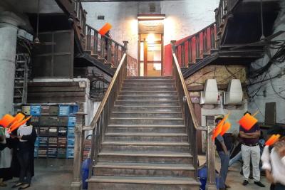 Wooden staircase leading to a lit doorway in a lawyers' chambers building, with people standing near lockers and boxes.