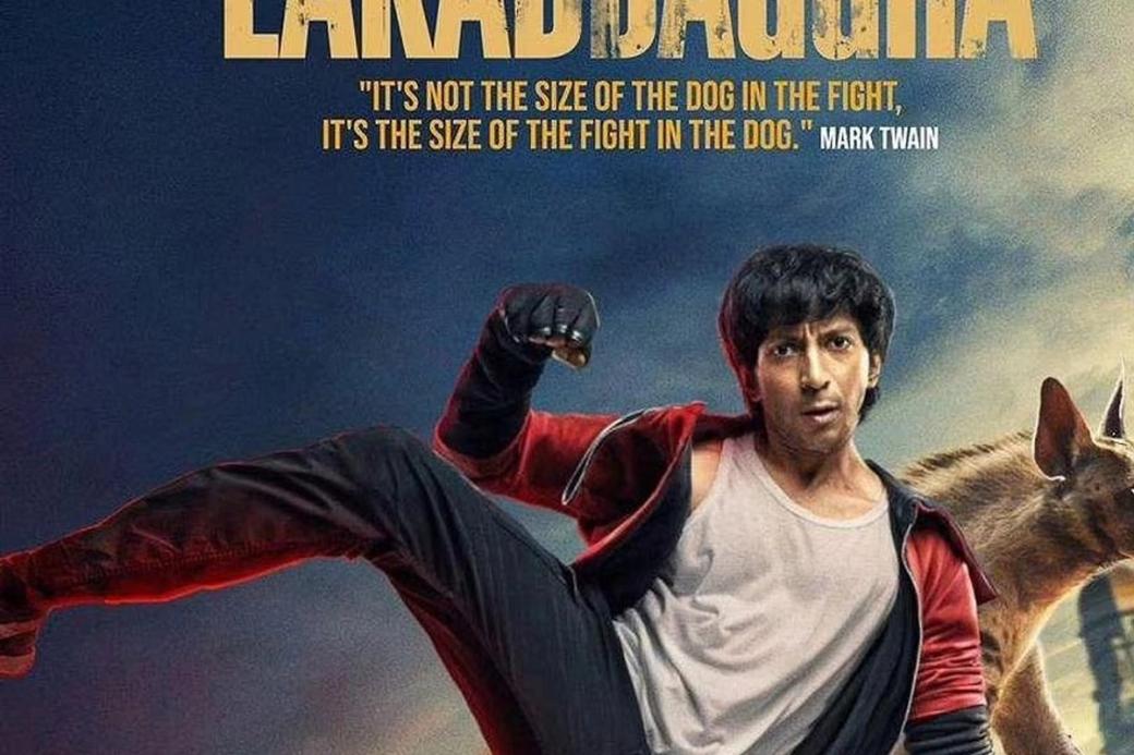 Film poster of a young man mid-kick on the roof of a yellow taxi, with a dog behind him and a red-and-grey title