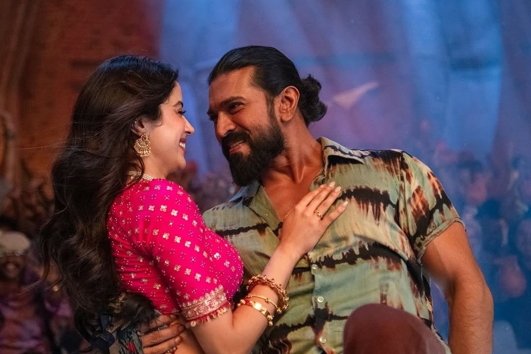 Janhvi Kapoor, in a pink blouse and gold jewellery, and Ram Charan, in a tie-dye shirt, smile at each other in a song from Peddi