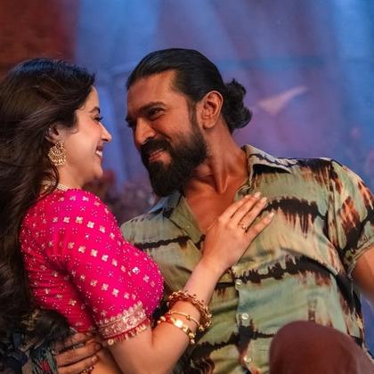 Janhvi Kapoor, in a pink blouse and gold jewellery, and Ram Charan, in a tie-dye shirt, smile at each other in a song from Peddi