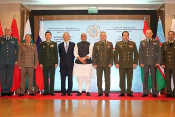 Defence ministers of SCO member states standing in a row before flags and a meeting backdrop, with Rajnath Singh in the centre