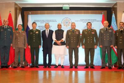 Defence ministers of SCO member states standing in a row before flags and a meeting backdrop, with Rajnath Singh in the centre