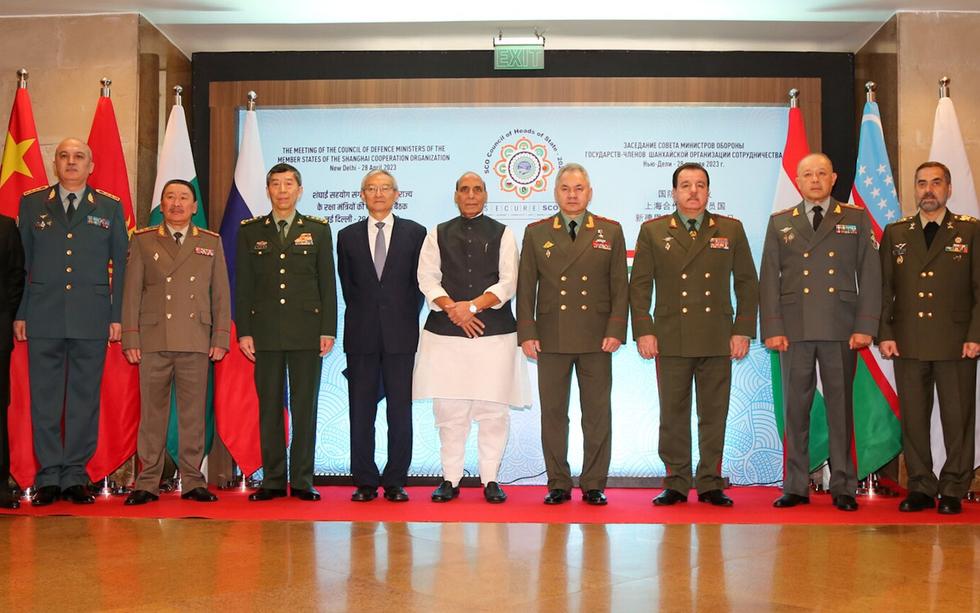 Defence ministers of SCO member states standing in a row before flags and a meeting backdrop, with Rajnath Singh in the centre