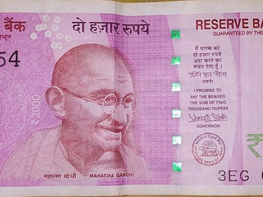 Front of a ₹2000 Indian banknote in pink-violet with a portrait, Reserve Bank of India text and a green ₹2000 numeral