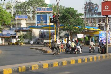Street junction with a Bharat Petroleum petrol pump canopy, scooters waiting at a signal and Bank of India signs