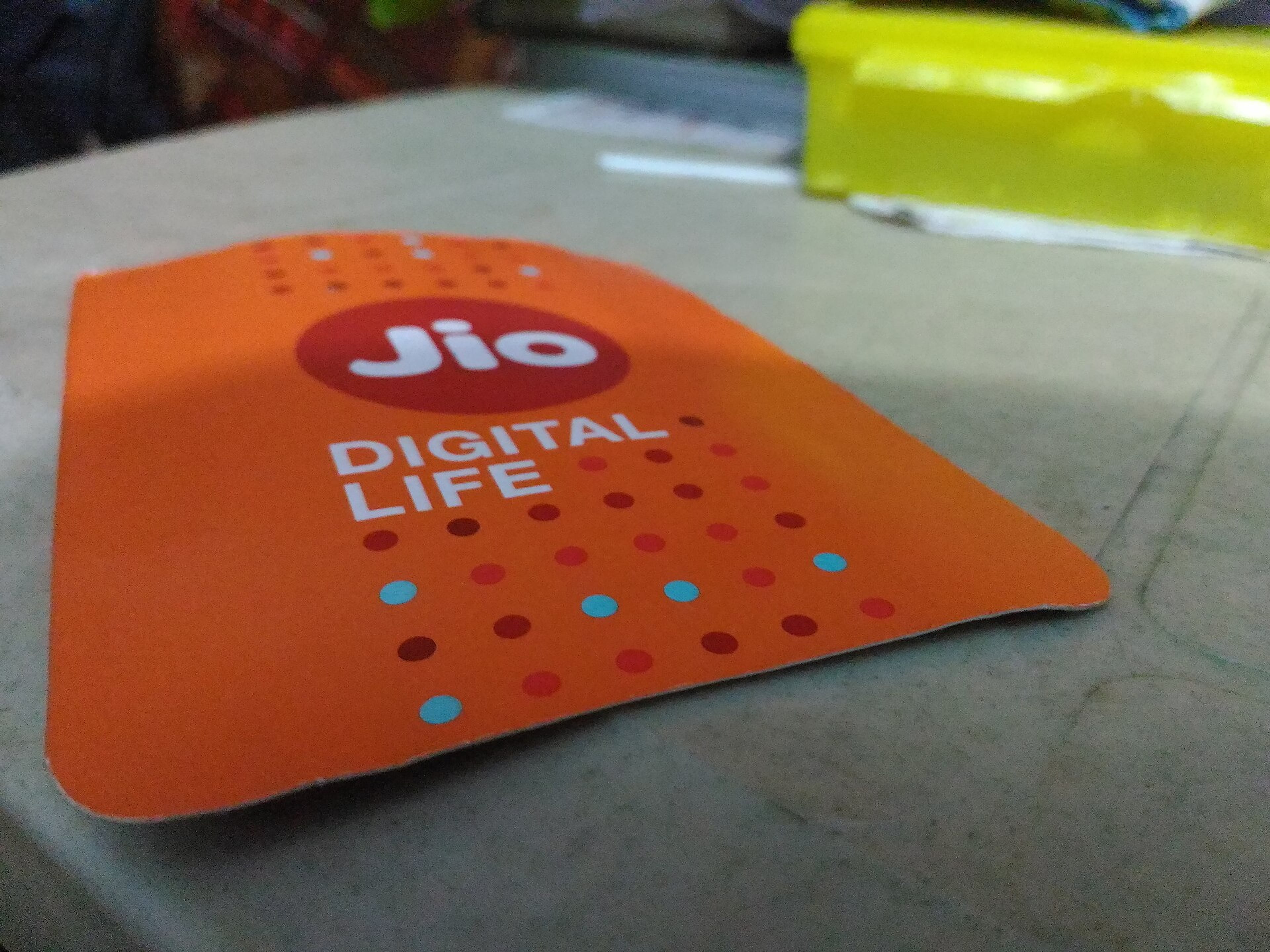 Close-up of an orange Jio Digital Life card with the Jio logo, resting on a table.