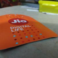 Close-up of an orange Jio Digital Life card with the Jio logo, resting on a table.