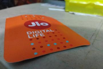 Close-up of an orange Jio Digital Life card with the Jio logo, resting on a table.