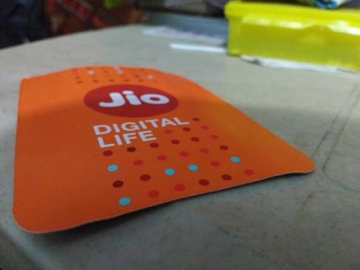 Close-up of an orange Jio Digital Life card with the Jio logo, resting on a table.
