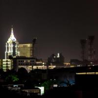 Night skyline of Bangalore with lit high-rise towers and a spire above dark rooftops and trees.