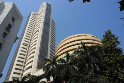 Curved cream-coloured high-rise and a round building seen from below, with palm trees and a blue sky