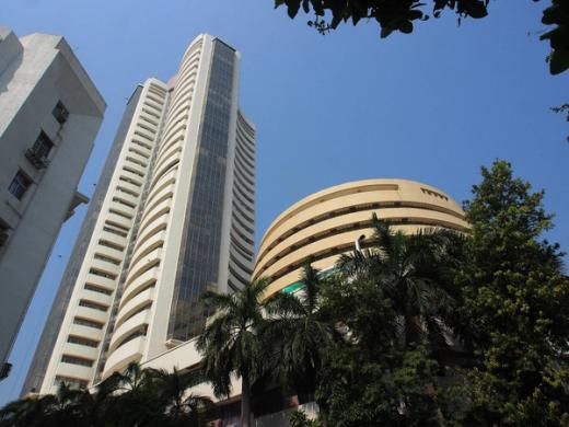 Curved cream-coloured high-rise and a round building seen from below, with palm trees and a blue sky