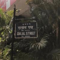 Blue Dalal Street sign in Hindi and English, with palm trees behind it.