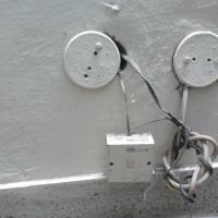 Telephone junction box on a painted wall with two round cover plates and loose cables coiled beneath