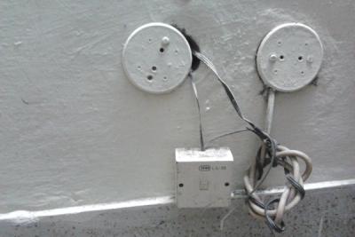 Telephone junction box on a painted wall with two round cover plates and loose cables coiled beneath