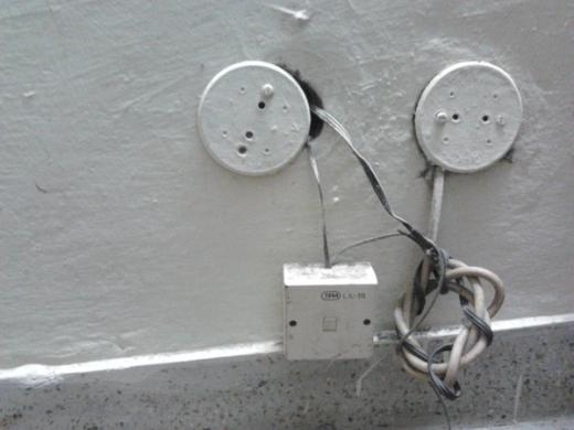 Telephone junction box on a painted wall with two round cover plates and loose cables coiled beneath