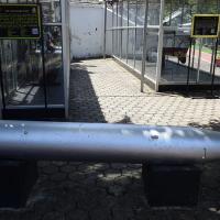 Silver torpedo lying on a paved outdoor area in front of glass display cases and information boards