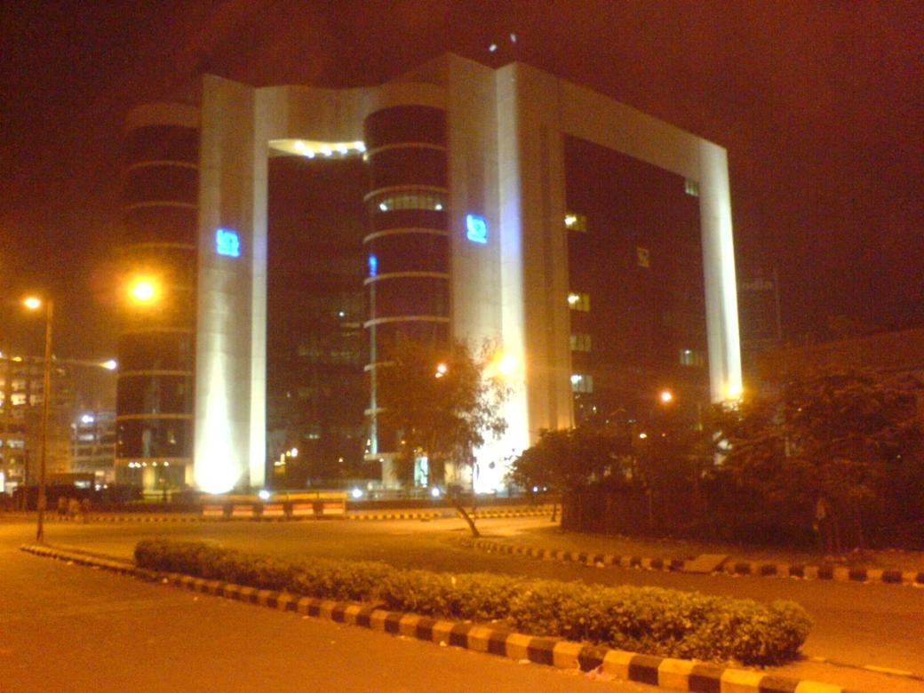 Night view of the SEBI building in Bandra Kurla Complex, its arched concrete frame lit against a dark sky.