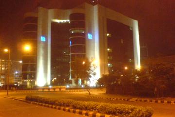 Night view of the SEBI building in Bandra Kurla Complex, its arched concrete frame lit against a dark sky.