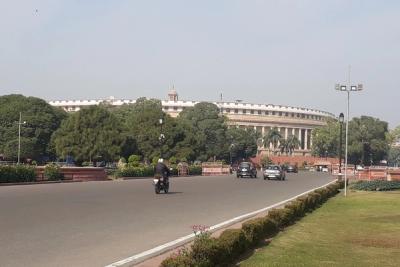 Motorcycle and cars on a wide road with lawns and a domed government building in the background, New Delhi