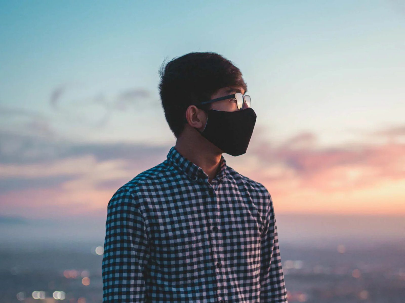 Crisis Trends 2020 cover: a man in a black face mask looks out over a city skyline at sunset.