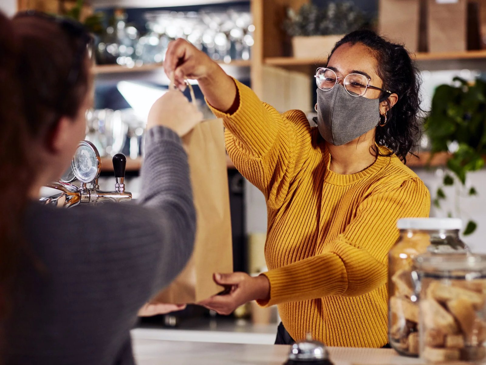 Consumer Trends 2022 cover: a shop assistant wearing a face mask hands a paper bag to a customer.