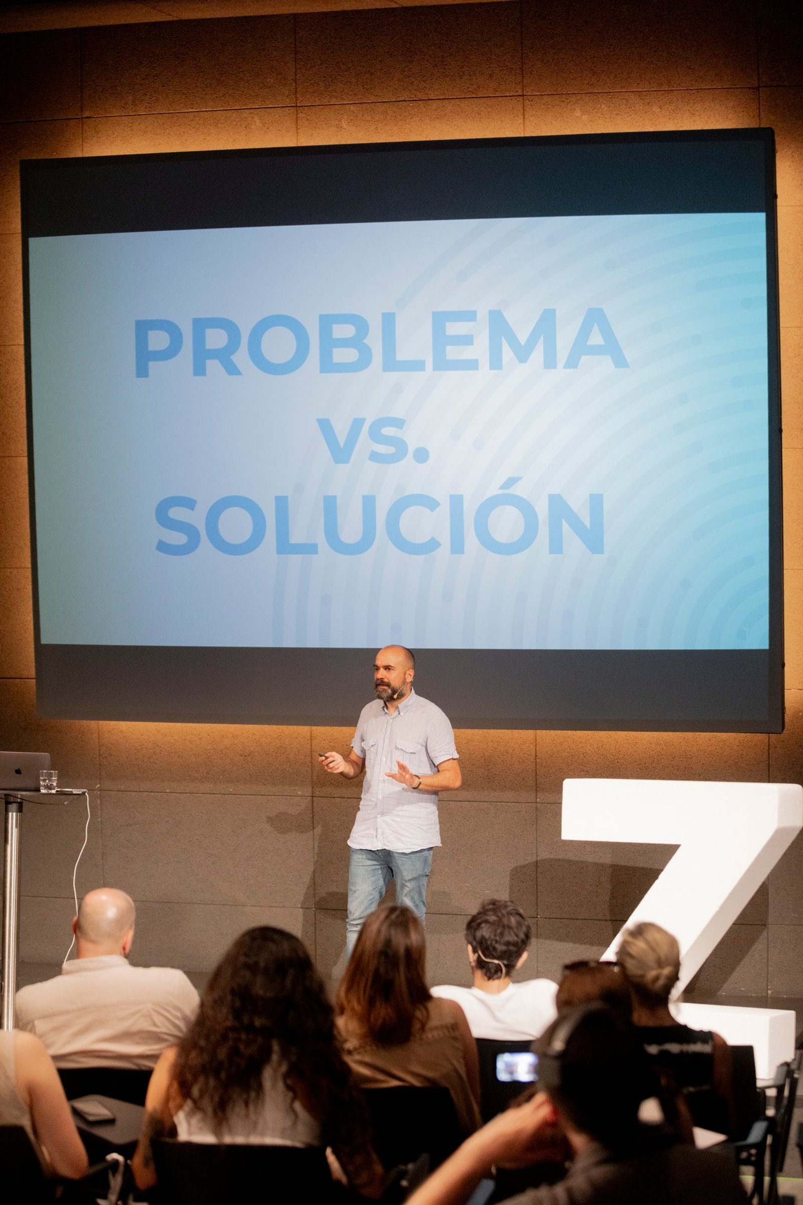 Speaker in front of the slide «Problem vs. solution», next to a large Z