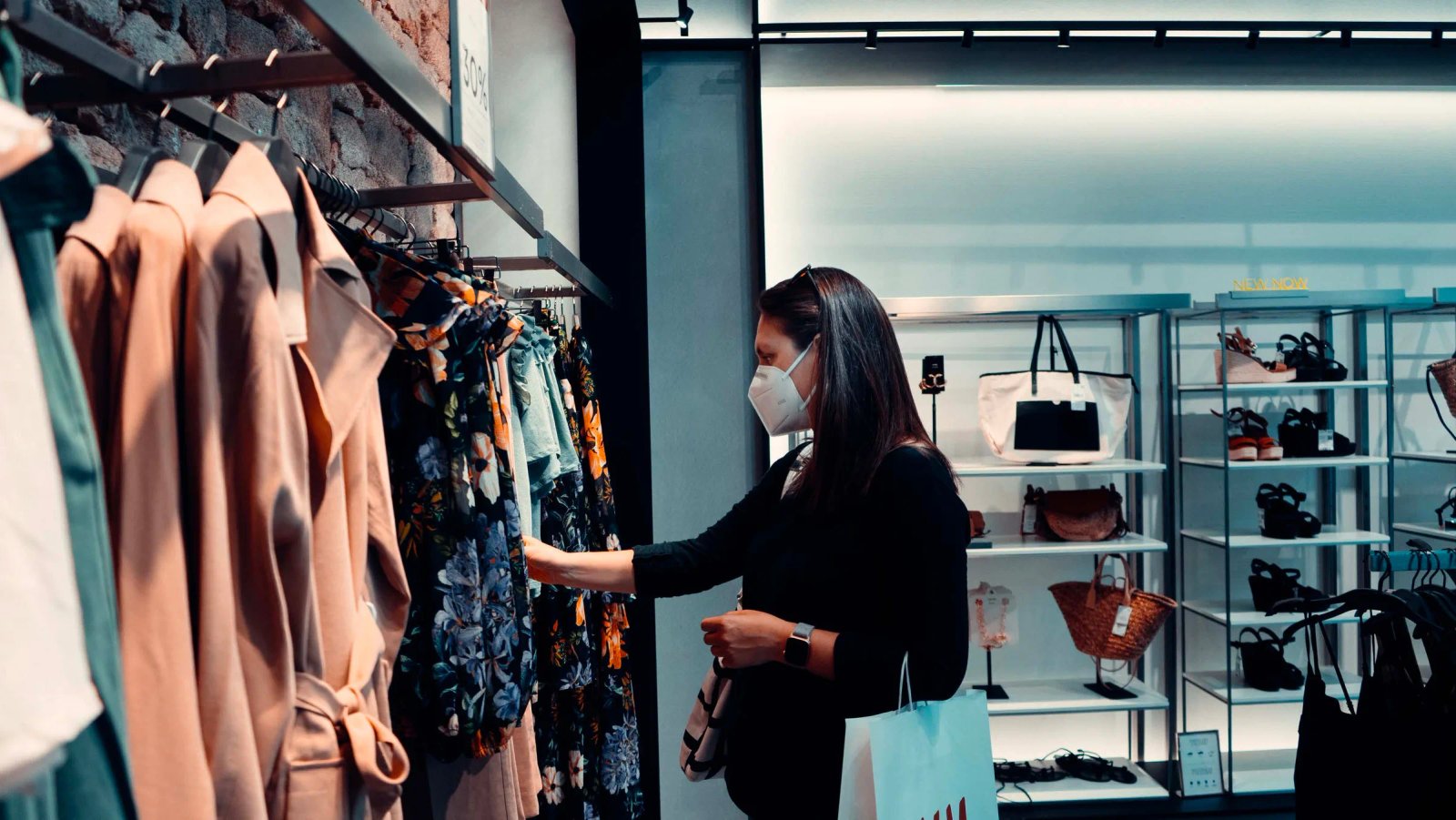 Portada de Consumer Trends 2021: una mujer con mascarilla mira ropa colgada en una tienda.