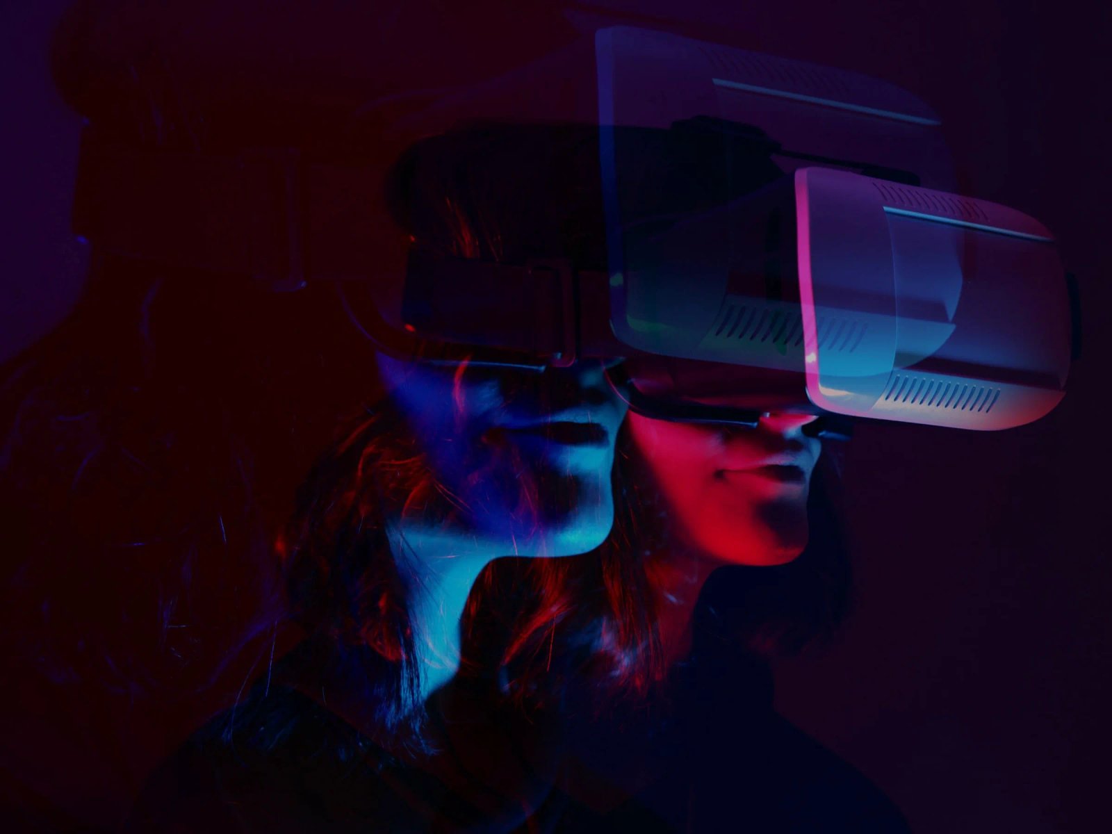 Portada de Metaverse Trends 2022: dos personas con gafas de realidad virtual, iluminadas con luz roja y azul.