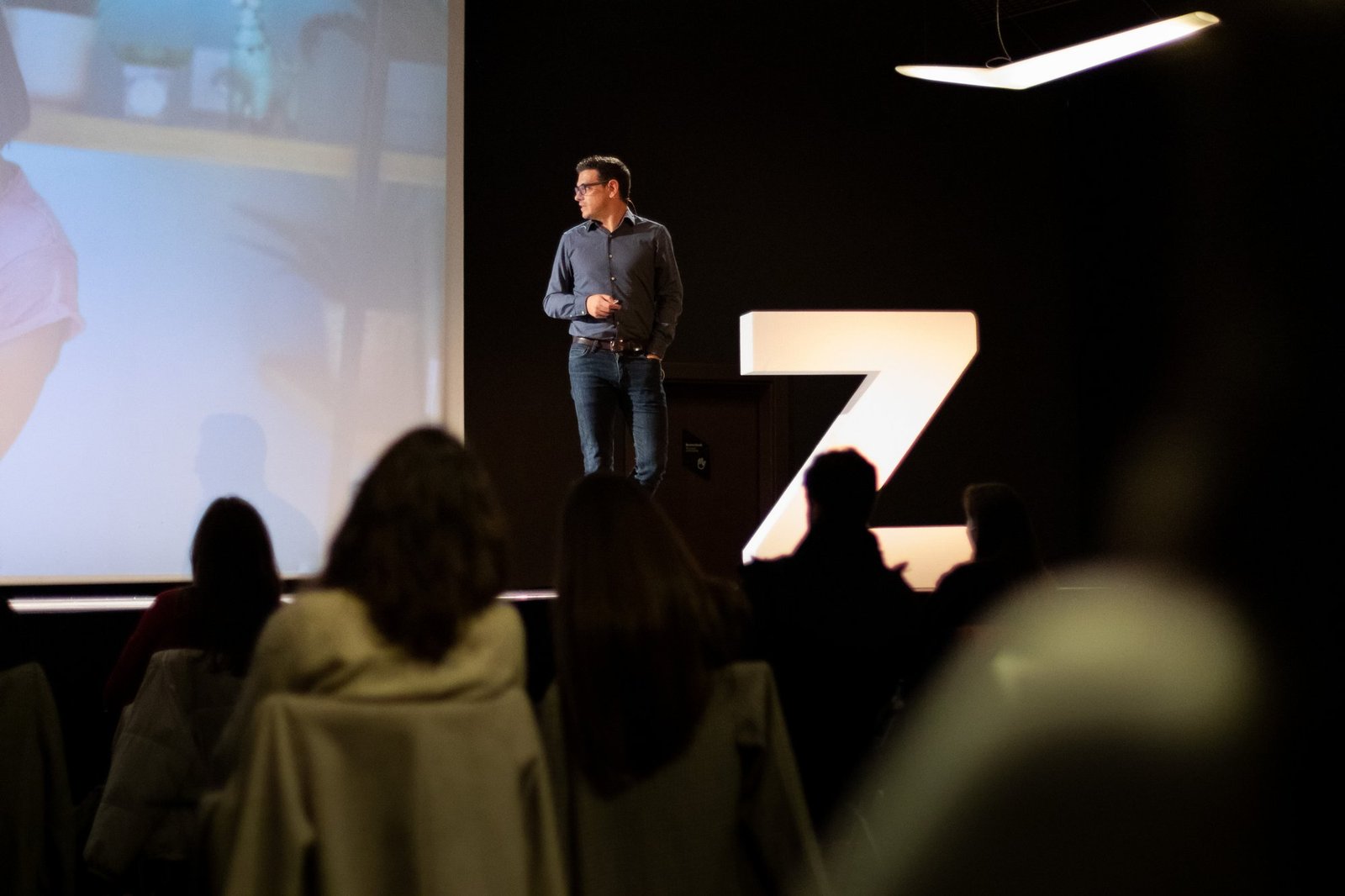Ponente en un escenario junto a una gran Z iluminada, ante el público