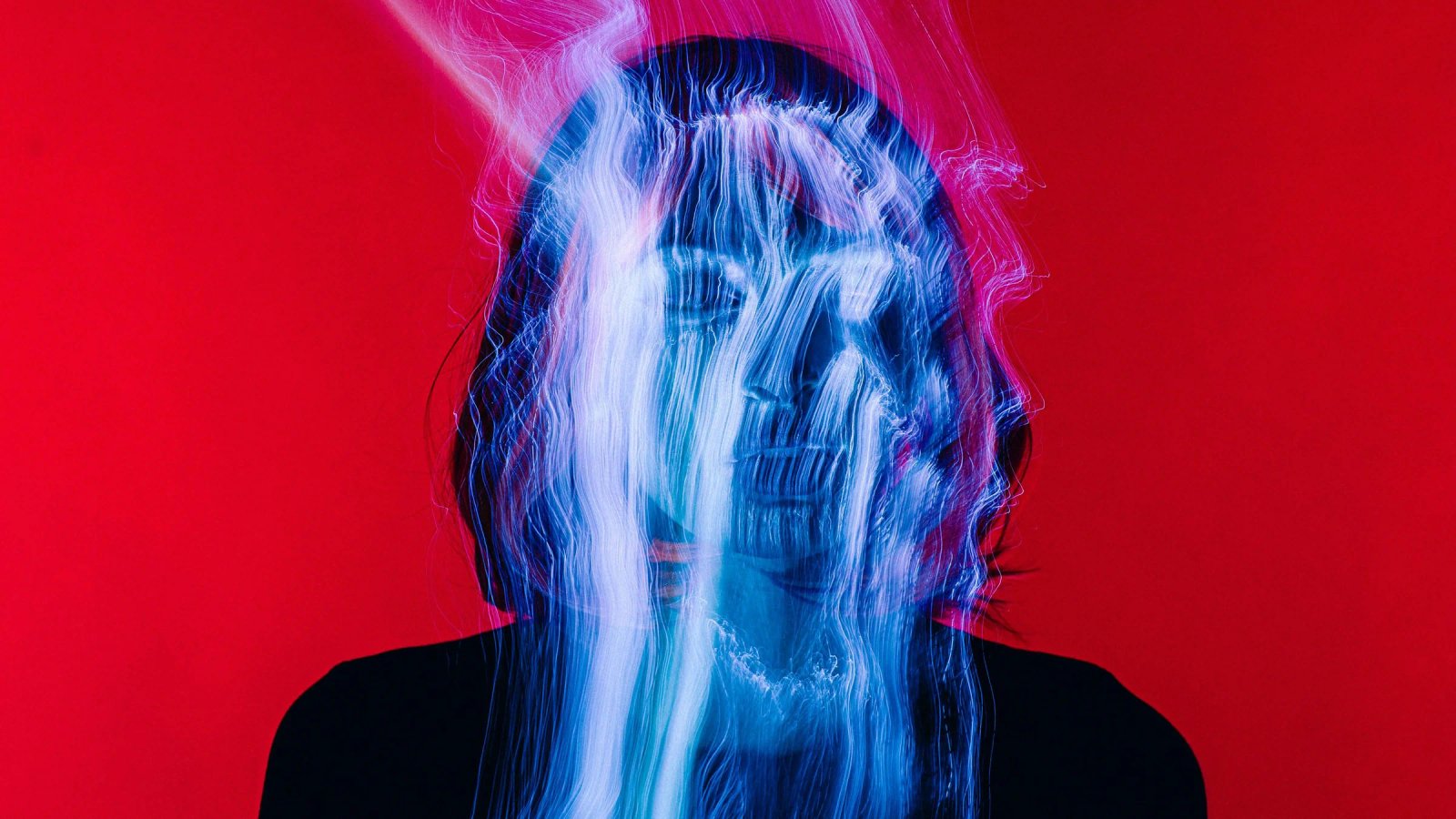 Portada de UX Trends 2025: el rostro de una persona sobre fondo rojo, cruzado por trazos de luz azul y rosa.