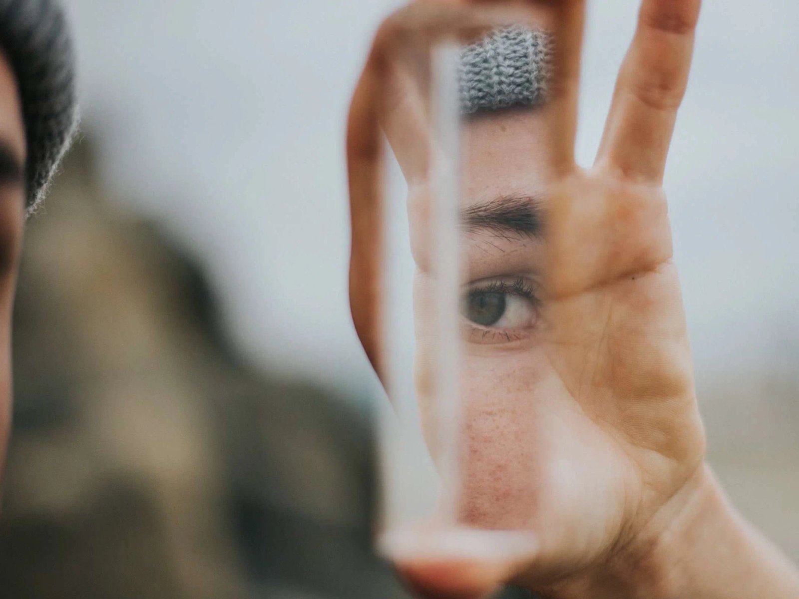 Portada de Consumer Trends 2024: una mano sostiene un prisma de cristal frente a la cara y deja ver un ojo a través de él.