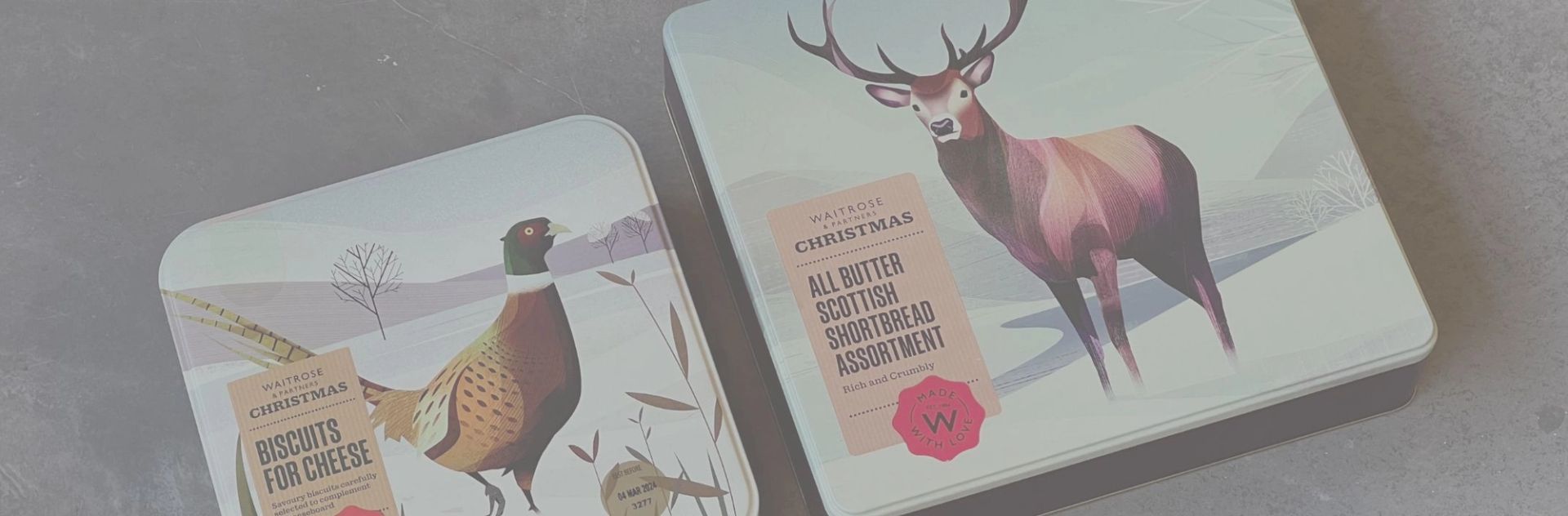 Two Waitrose Christmas tins: one with a pheasant for biscuits, the other with a stag for shortbread.
