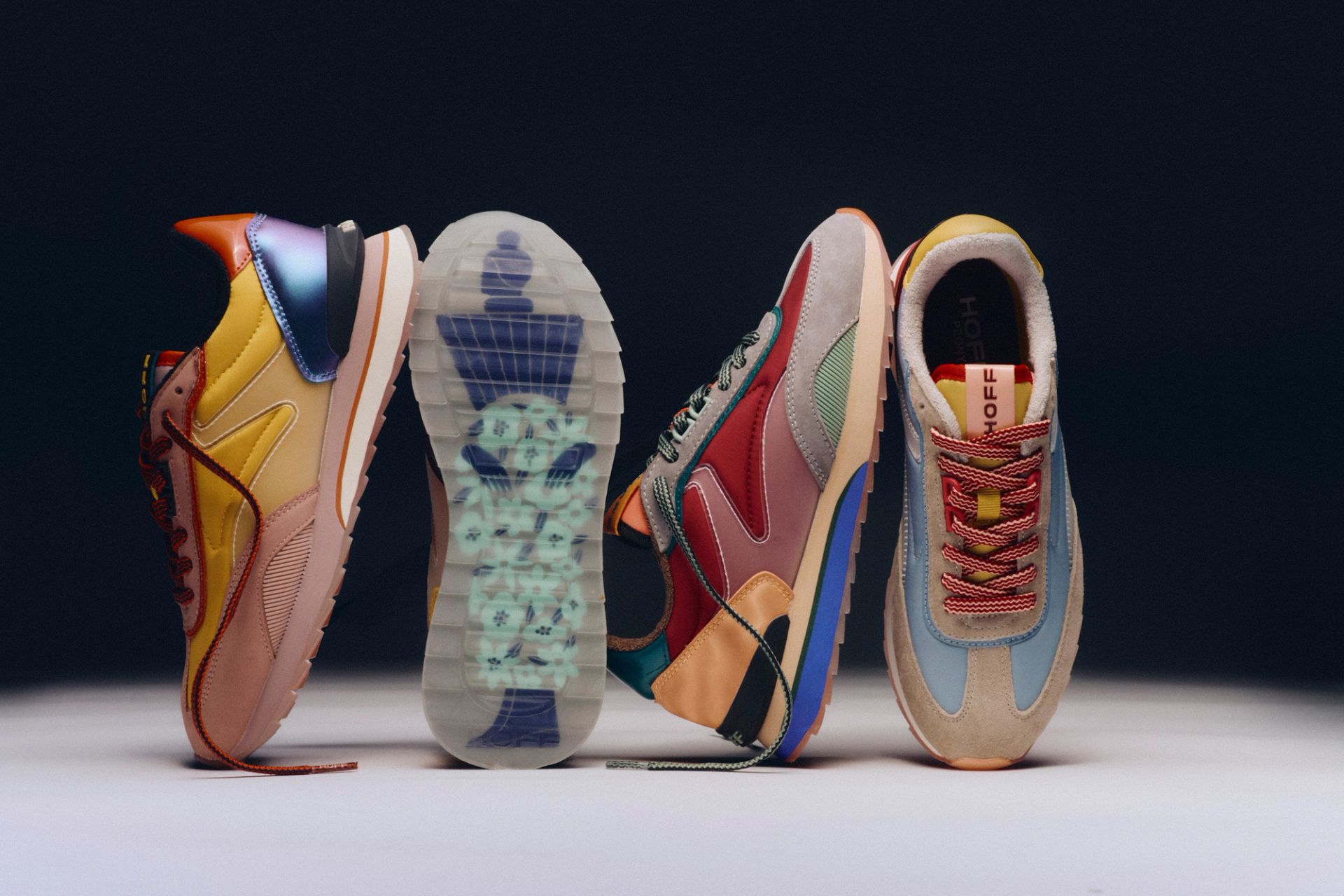 Four colorful Hoff brand sneakers, two standing upright, one displaying a chess king on its translucent sole.