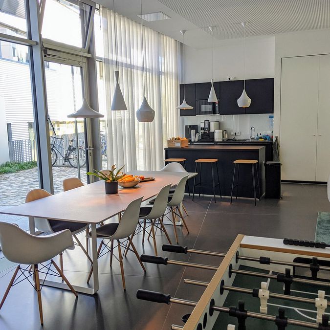 Offene Küche im Jurodo-Büro mit langem Esstisch, Tresen und Kicker