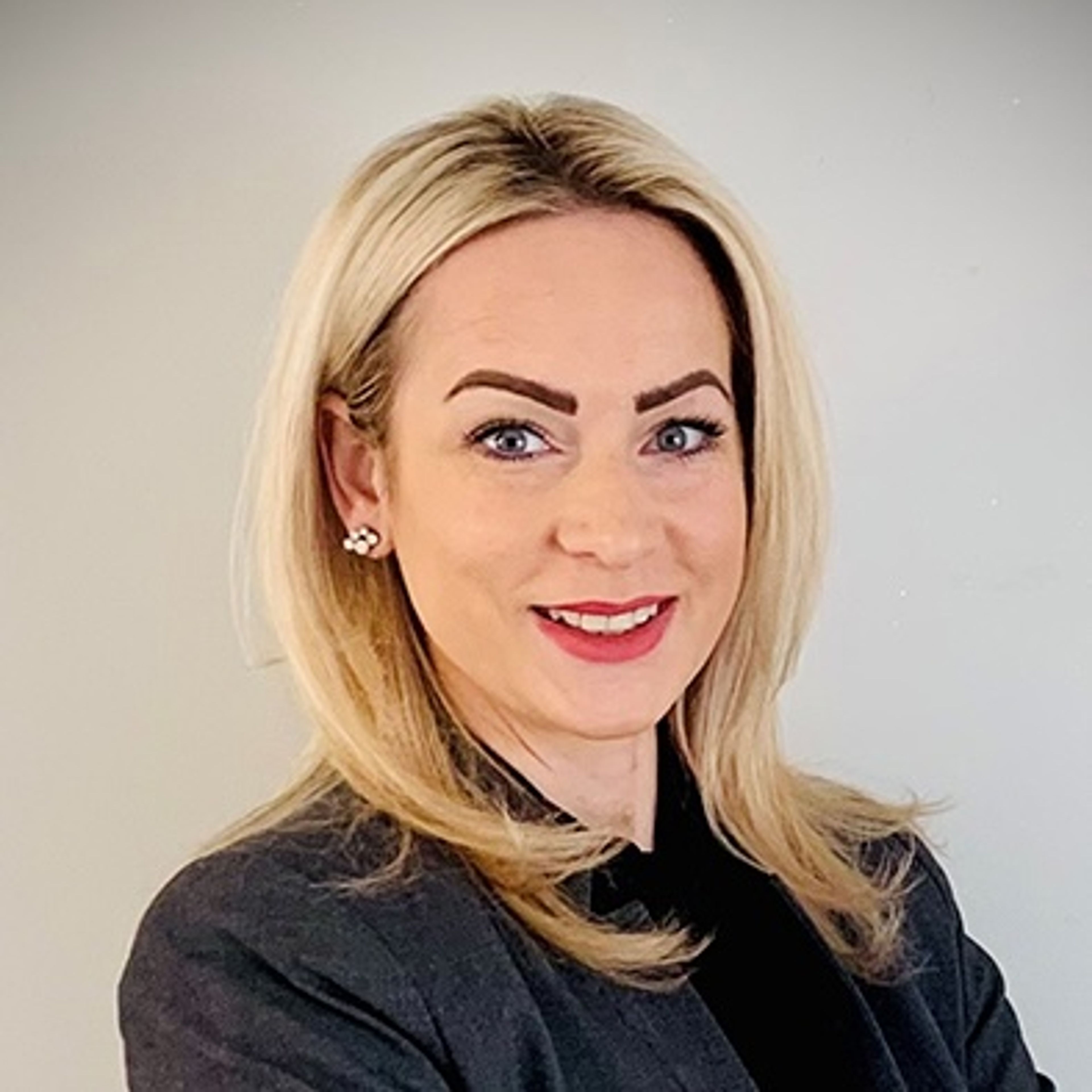 Smiling blonde woman in a dark blazer.