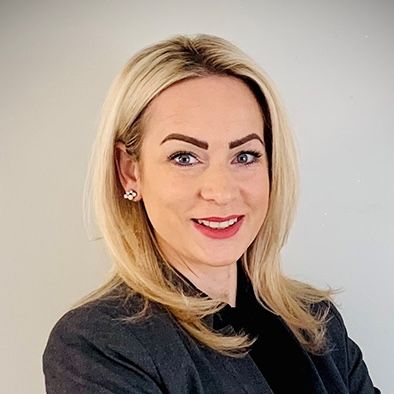 Smiling blonde woman in a dark blazer.