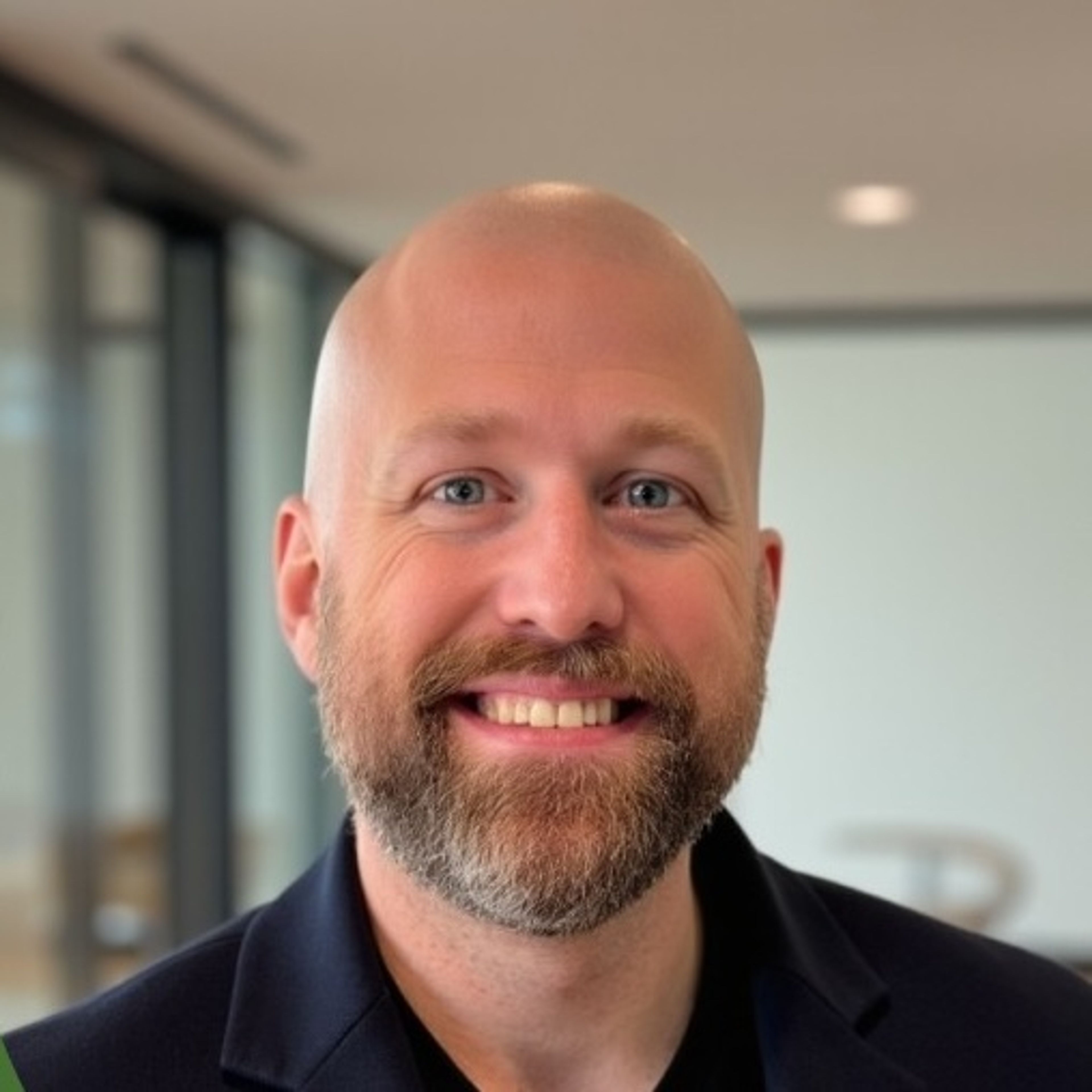 Headshot of a smiling bald man with a beard.