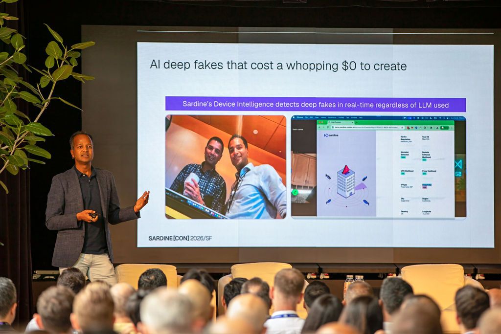 A man presents about AI deep fakes and Sardine's detection technology to a seated audience, with a presentation slide visible.