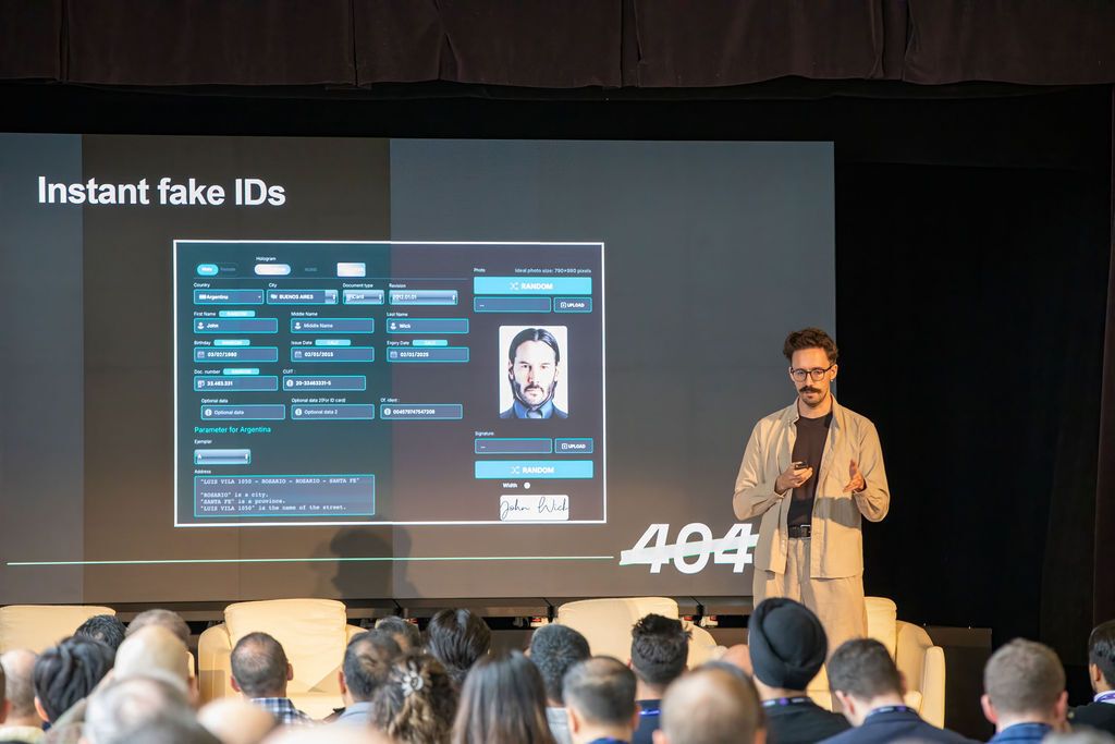 A presenter on stage stands next to a screen displaying an "Instant fake IDs" interface with a photo of Keanu Reeves.