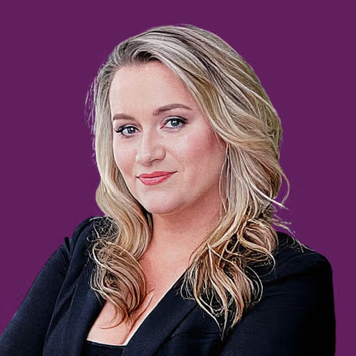 A blonde woman in a black blazer smiles slightly against a purple background.