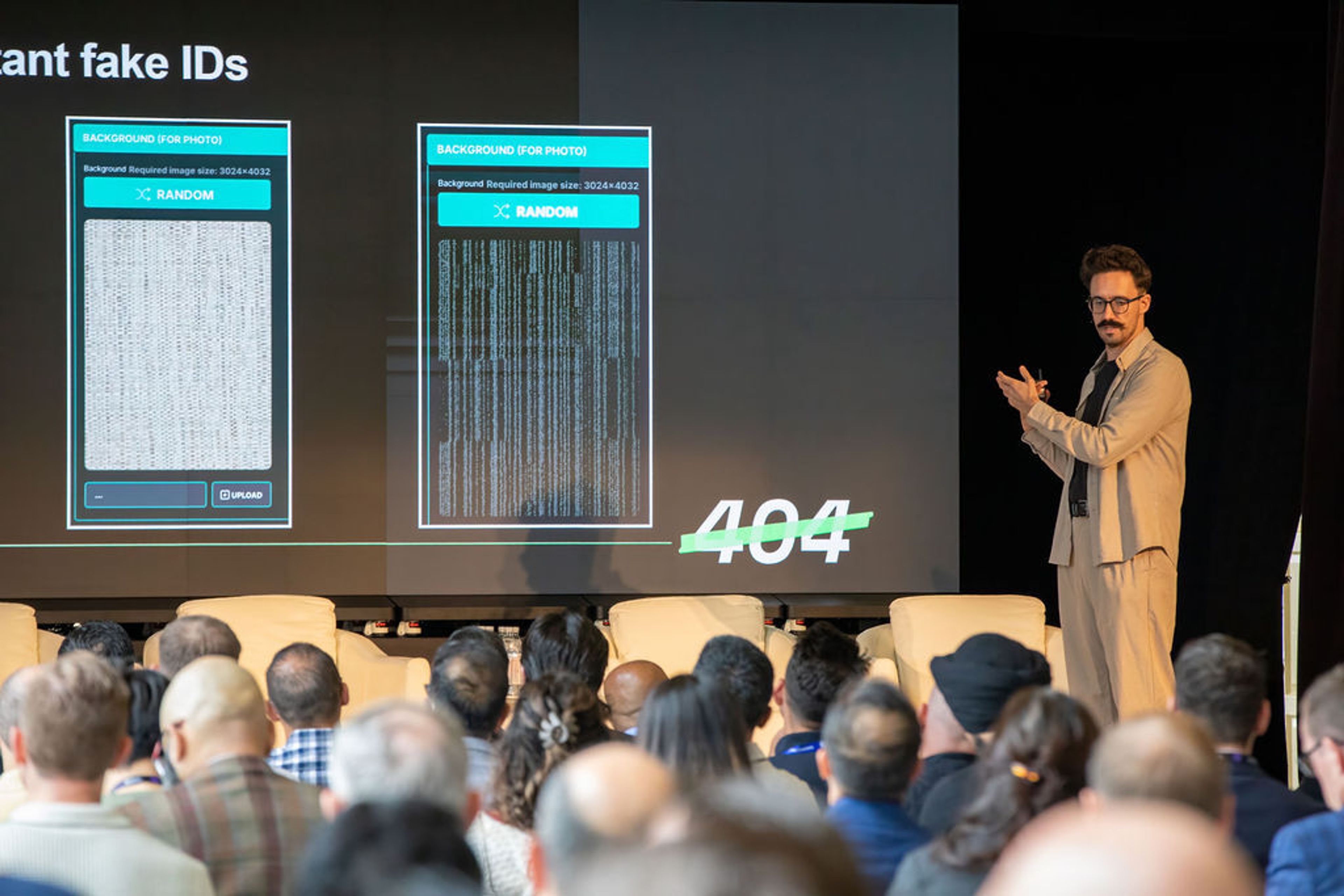A man presents on stage to an audience, with a screen behind him showing two app interfaces displaying random textured backgrounds, a crossed-out "404," and the partial title "fake IDs."
